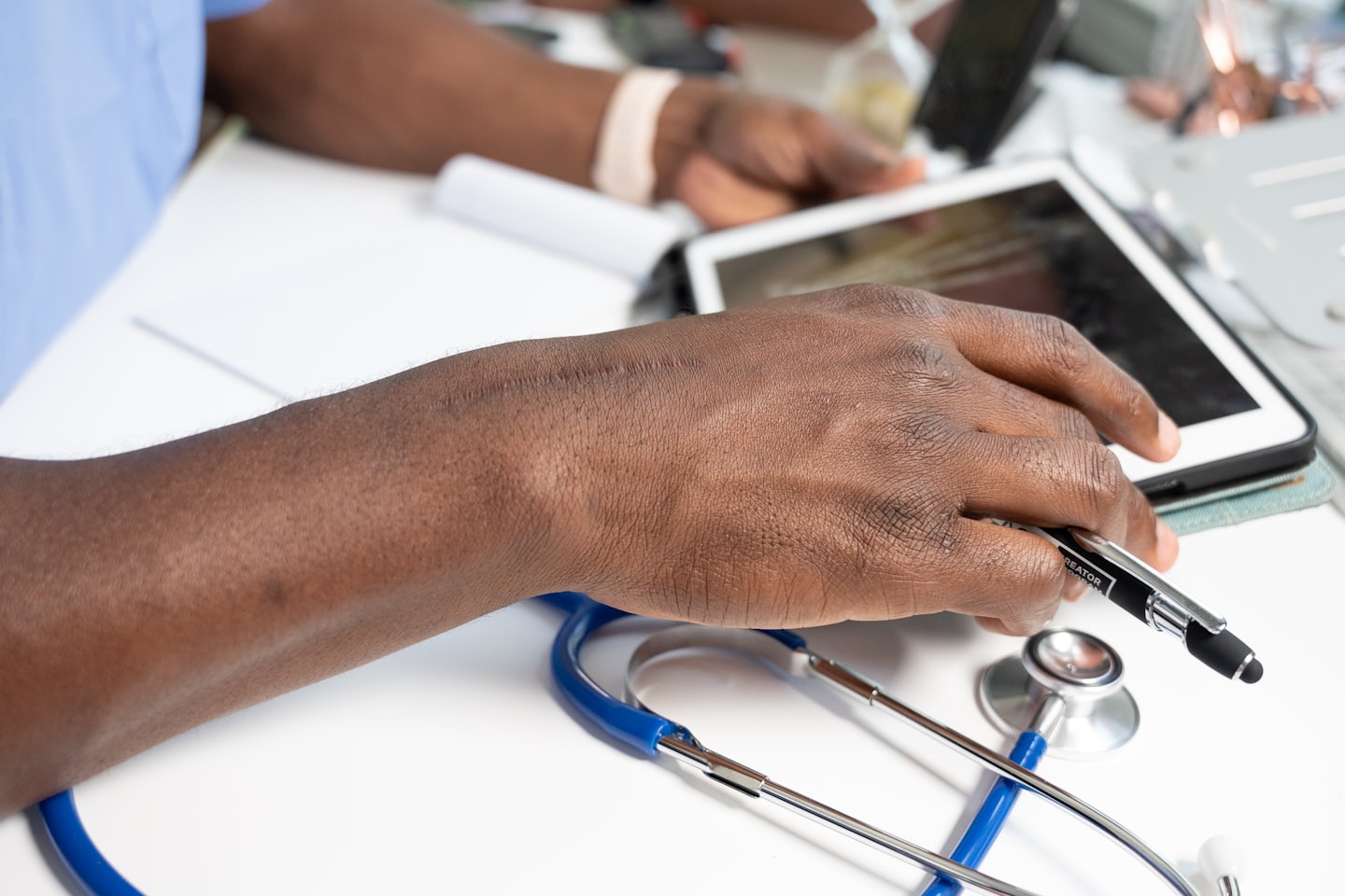 Doctor using a tablet with a stylus on a desk.
