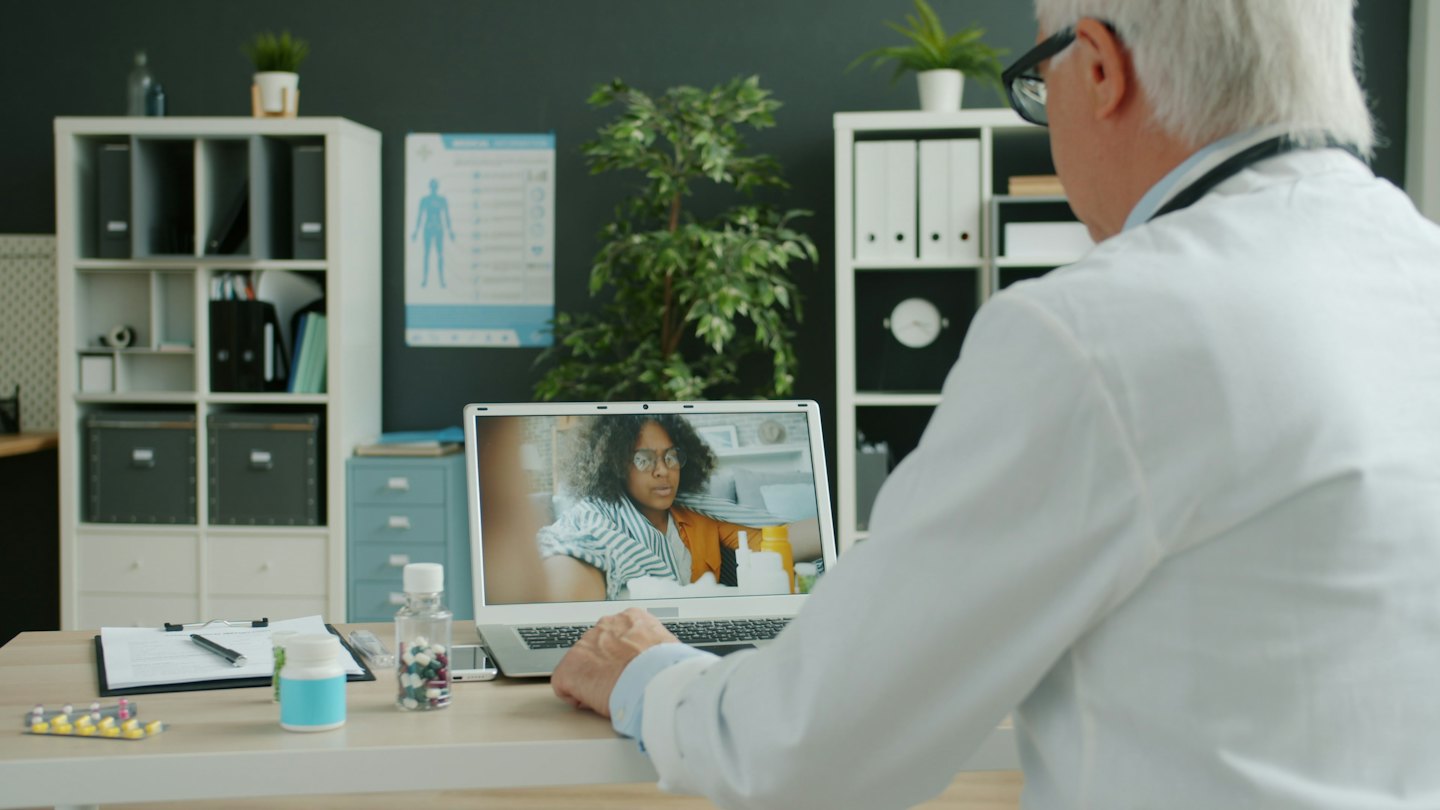 Doctor consults with patient on laptop during telemedicine appointment.