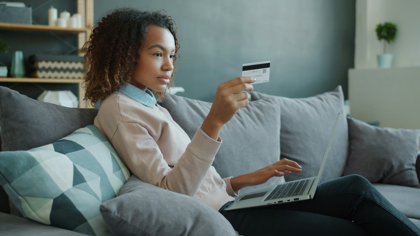 Woman sits on a sofa shopping online with her laptop.