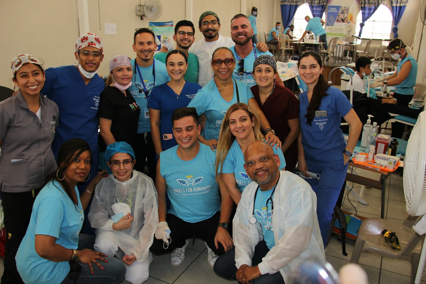 Volunteers in matching t-shirts pose for a group photo at a health clinic.